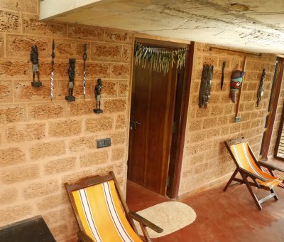 The wall of the verandah is adored by African artifacts. Also give some rest with those arm-chairs.